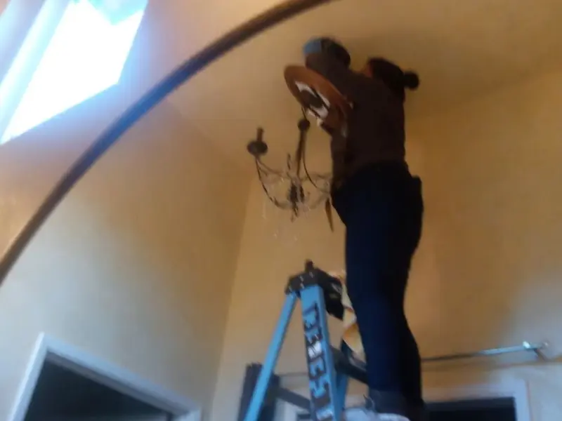 Electrician installing a chandelier in a Dover residence
